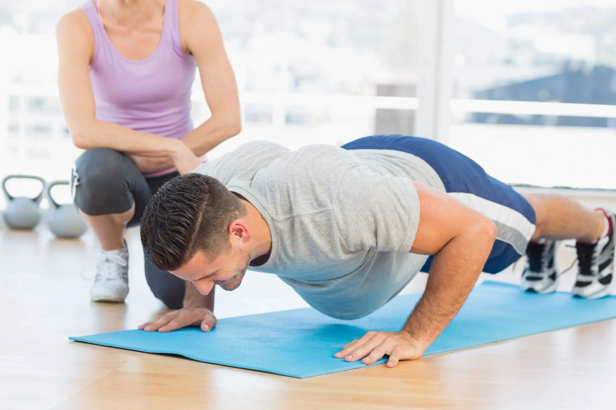 Man doing push-ups on a yoga mat with instructor guidance.
